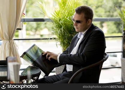 Young Businessman holding a menu sitting in a summer restaurant