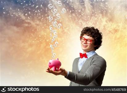 Young businessman holding moneybox. Image of young businessman in red glasses holding moneybox