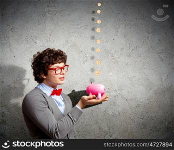 Young businessman holding moneybox. Image of young businessman in red glasses holding moneybox
