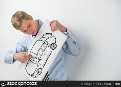 Young businessman holding sign with car sketch. Automobile dealer or credit agent