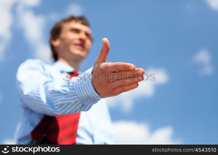 young businessman in a blue shirt and red tie giving a hand for a handshake