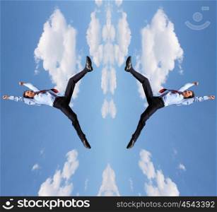 young businessman in a blue suit jumping in the air against blue sky
