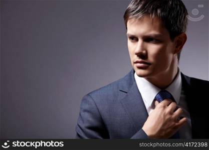 Young businessman in a business suit with a gray background