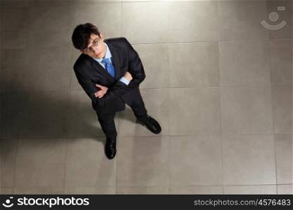 Young businessman in glasses. Image of young businessman in glasses arms crossed. Top view