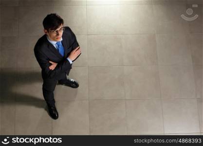 Young businessman in glasses. Image of young businessman in glasses arms crossed. Top view