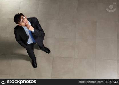 Young businessman in glasses. Image of young businessman in glasses looking thoughtfully. Top view