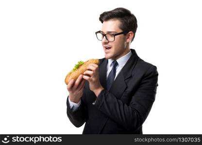 Young businessman in glasses, tie and black suit eats burger, isolated on white background