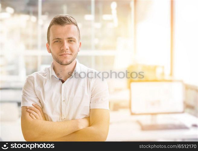 Young businessman in his office. Portrait of young junior businessman in front of his big modern office