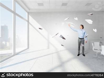 Young businessman in modern office with paper plane in hand