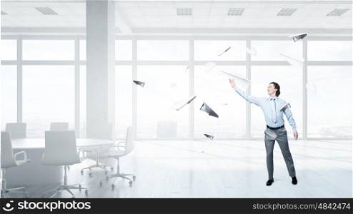 Young businessman in modern office with paper plane in hand