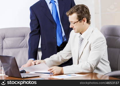 Young businessman in office showing documents to his boss