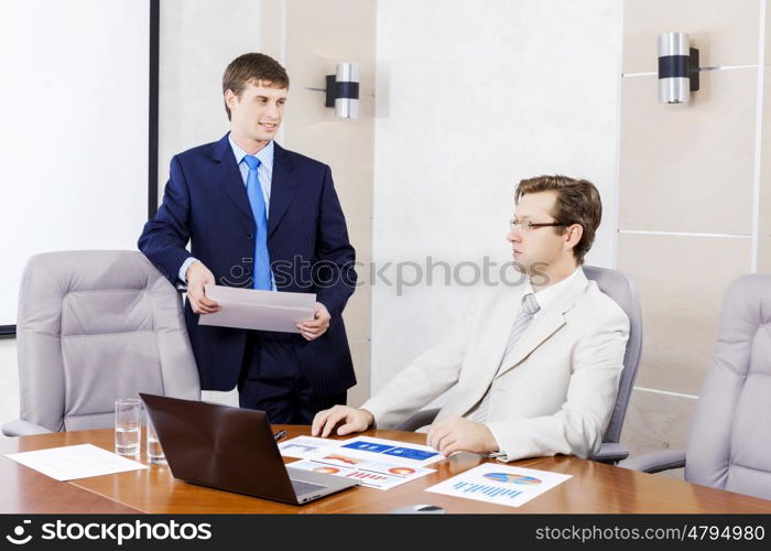 Young businessman in office showing documents to his boss