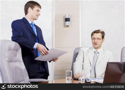 Young businessman in office showing documents to his boss