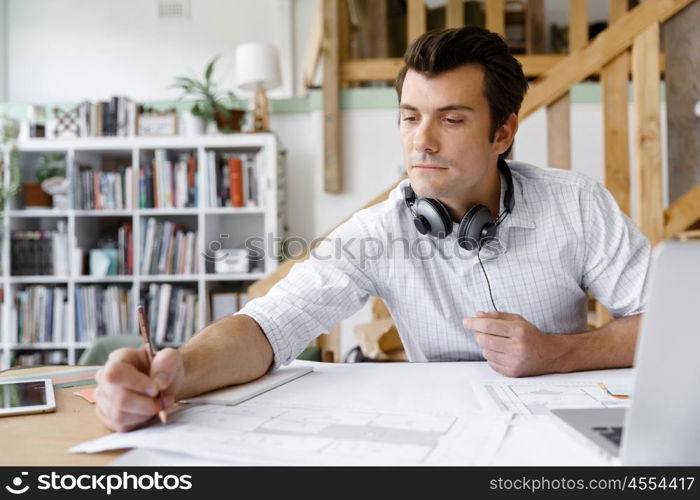 Young businessman in office. Young businessman working in office with headphones