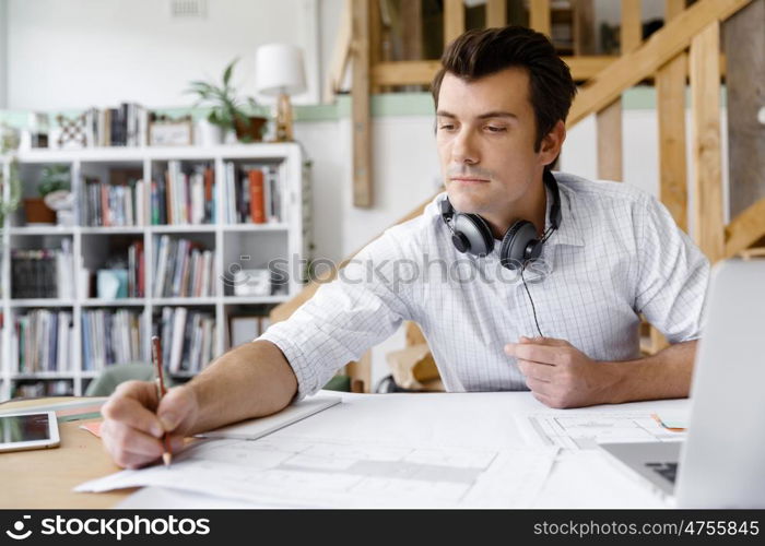 Young businessman in office. Young businessman working in office with headphones