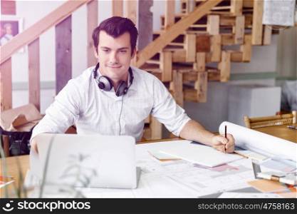 Young businessman in office. Young businessman working in office with headphones