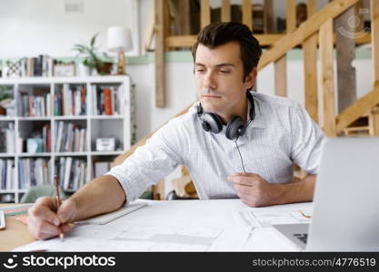 Young businessman in office. Young businessman working in office with headphones