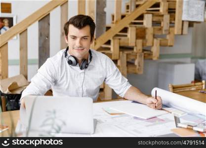 Young businessman in office. Young businessman working in office with headphones