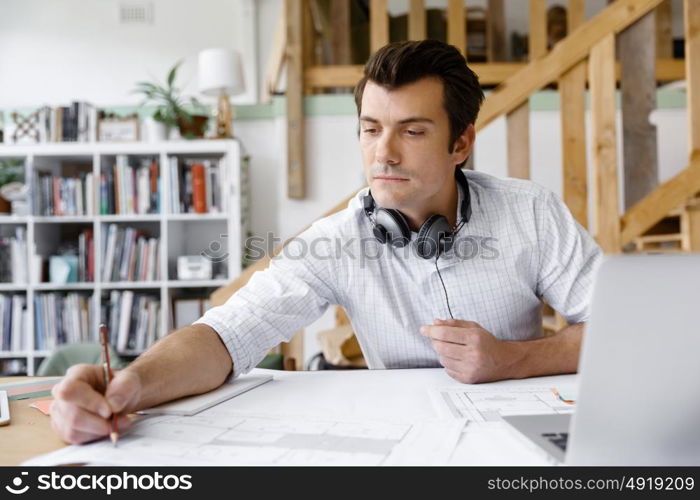 Young businessman in office. Young businessman working in office with headphones