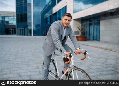 Young businessman in suit on the bicycle in downtown. Business person on eco transport on city street