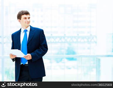 Young businessman in suit working in bright office, standing