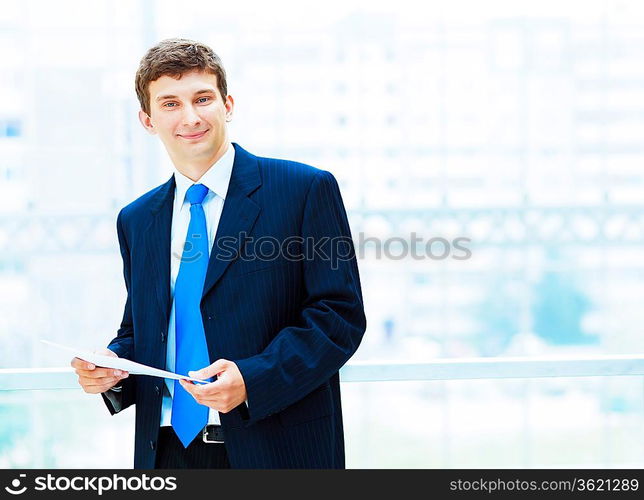 Young businessman in suit working in bright office, standing