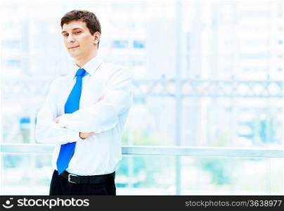 Young businessman in suit working in bright office, standing
