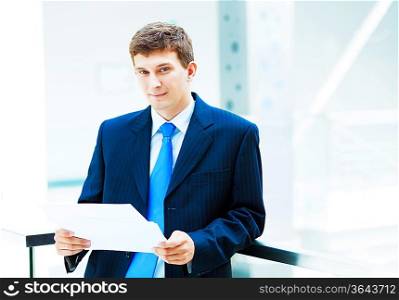 Young businessman in suit working in bright office, standing
