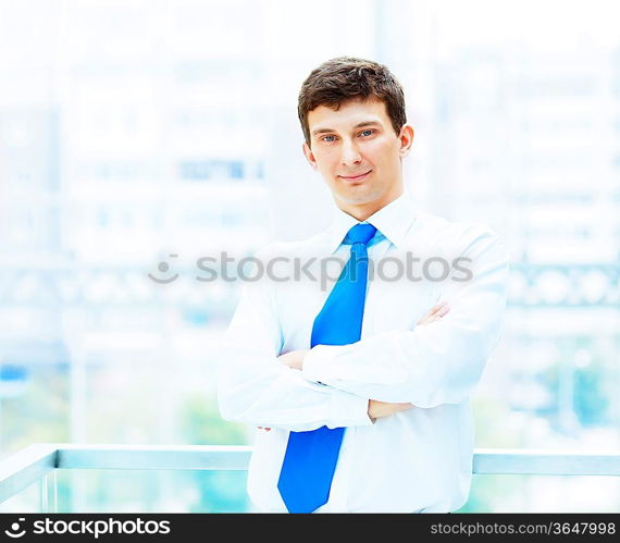 Young businessman in suit working in bright office, standing