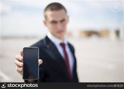 young businessman in suit. young businessman in suit showing smartphone screen