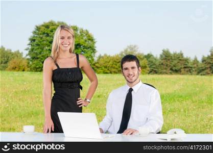 Young businessman in sunny nature have coffee with female colleague