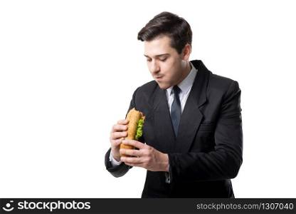 Young businessman in tie and black suit eats hot dog, isolated on white background