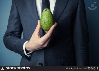 Young businessman is holding a green avocado
