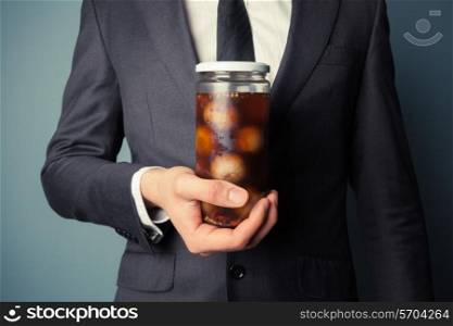 Young businessman is holding a jar of pickled onions