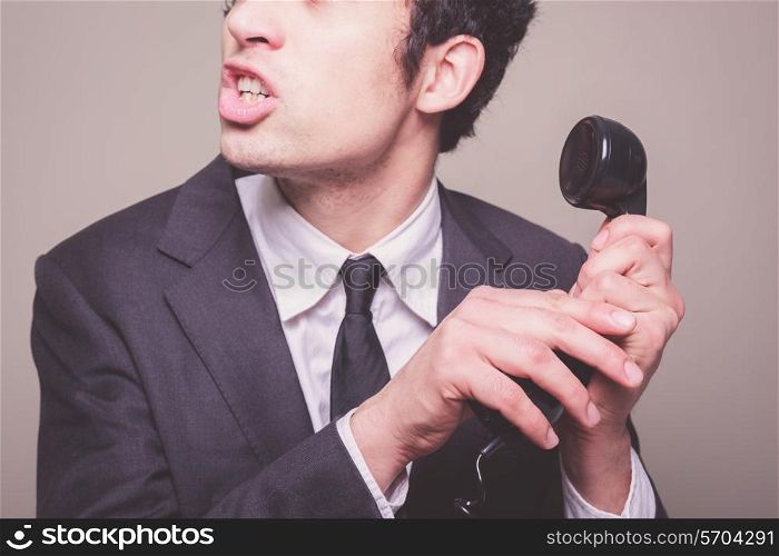 Young businessman is hushing someone in order to hear the phone