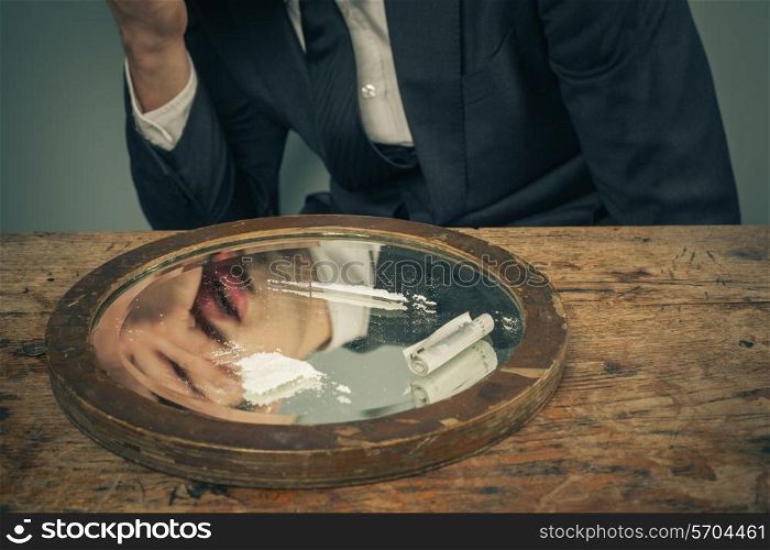Young businessman is snorting cocaine with a rolled up banknote