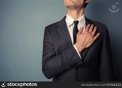 Young businessman is swearing allegiance with his hand on his chest