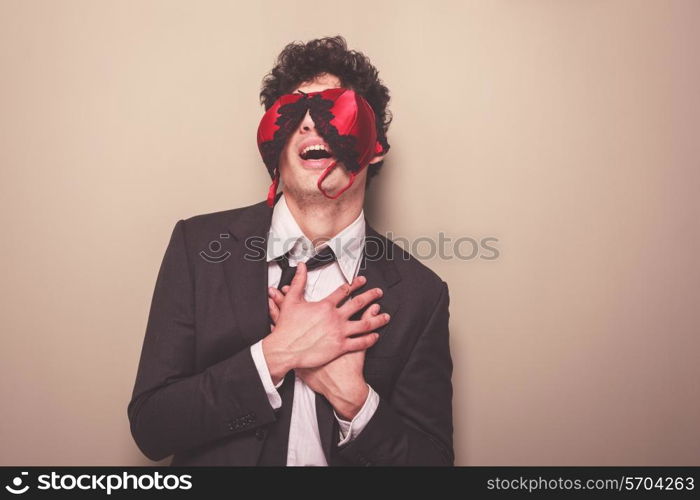 Young businessman is wearing a sexy bra on his face