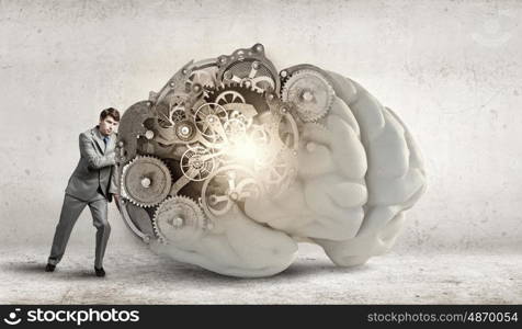 Young businessman leaning on big brain model. Man of great mind