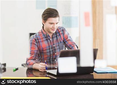 Young businessman looking at laptop on office desk