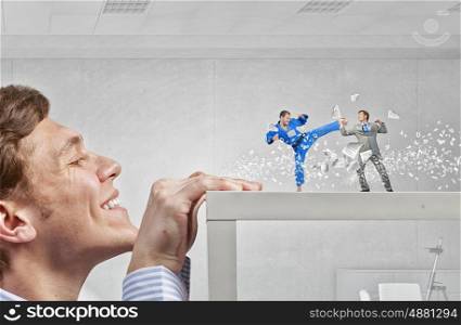 Young businessman looking from under table on fighting people. Businessman peeping from under table