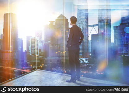 Young businessman looking out the city in the office . morning scene. .