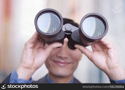 Young businessman looking through binoculars, Beijing