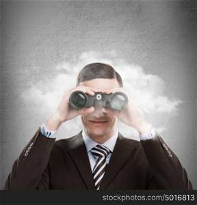 Young businessman looking through binoculars - market research concept