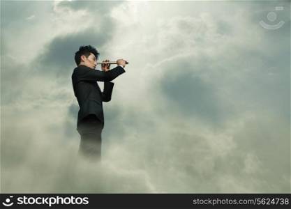Young businessman looking through telescope in a dreamlike cloud