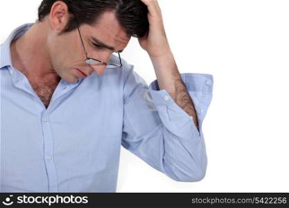 young businessman looking tired with glasses lowered and hand to his head