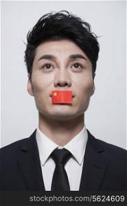 Young businessman looking up with a Chinese flag covering his mouth