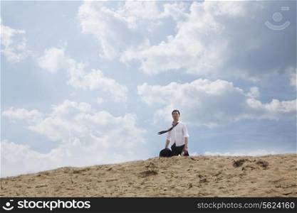 Young businessman lost and walking through the desert, distant