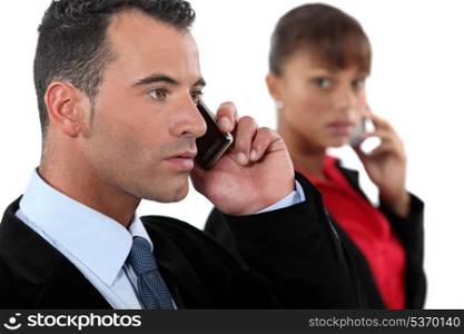 young businessman making a call and female colleague in background