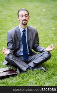 Young businessman meditating in the garden